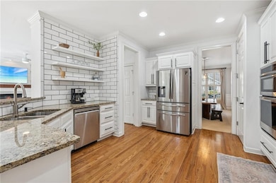 Kitchen with appliances with stainless steel finishes, open shelves, backsplash, white cabinetry, and ornamental molding