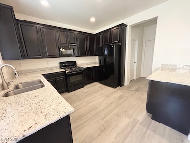 Kitchen featuring black appliances, light stone co