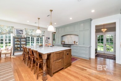 Kitchen with healthy amount of natural light, light wood finished floors, light stone countertops, a large island with sink, and recessed lighting