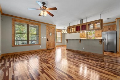 Unfurnished living room featuring dark wood-type flooring, crown molding, a chandelier, and ceiling fan