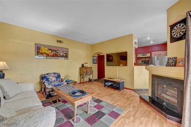Living area featuring arched walkways, wood finished floors, a tile fireplace, and baseboards