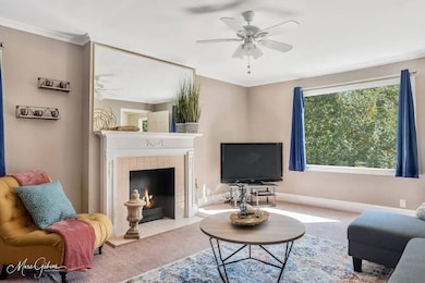 Living room with ceiling fan, carpet flooring, and a fireplace