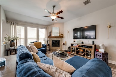 Living area with a tile fireplace, wood finished floors, and a ceiling fan