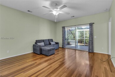 Sitting room featuring ceiling fan, wood-type floo