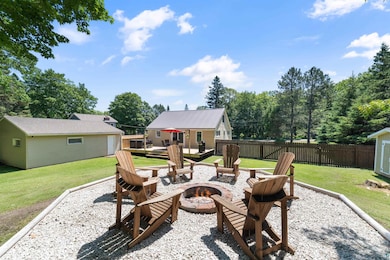 View of patio featuring an outdoor fire pit, a deck, and an outdoor structure