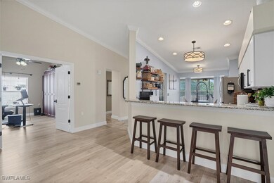 Kitchen with freestanding refrigerator, ornamental molding, light wood-style floors, a breakfast bar area, and white cabinets