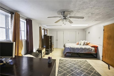 Bedroom featuring light tile patterned floors, multiple closets, a ceiling fan, a textured ceiling, and crown molding