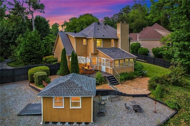 Back of property at dusk with a sunroom, a fenced backyard, a wooden deck, a shingled roof, and a chimney