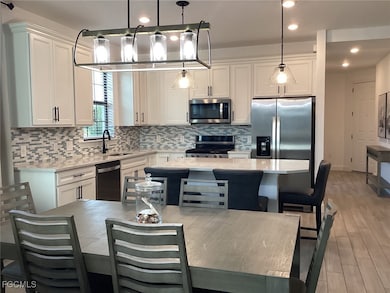 Kitchen featuring tasteful backsplash, decorative light fixtures, white cabinetry, light stone counters, and recessed lighting