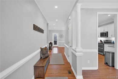 Hallway with crown molding, hard wood flooring, an