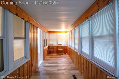Unfurnished sunroom with wood finished floors and wood walls