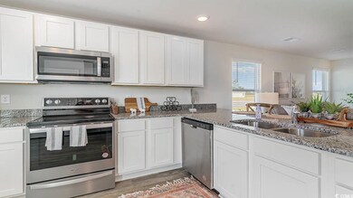 Kitchen with white cabinets, appliances with stain