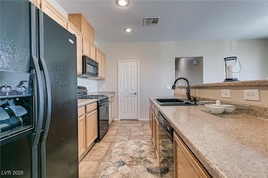Kitchen with black appliances, a sink, light brown