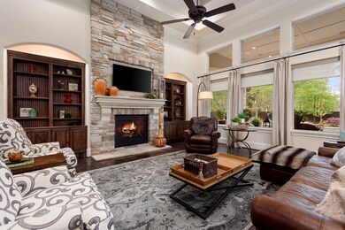 Spacious and inviting family room with a floor-to-ceiling stone, gas fireplace, built-ins with accent lighting, and wood flooring!