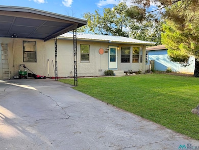 View of front of property featuring stucco siding, a front yard, an attached carport, a metal roof, and driveway