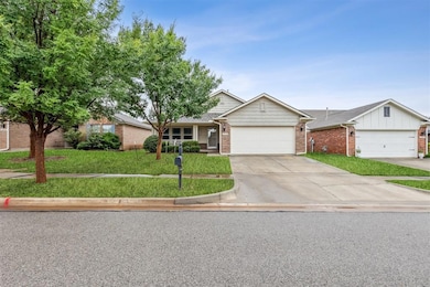Front facade with brick siding, a front yard, an attached garage, and concrete driveway