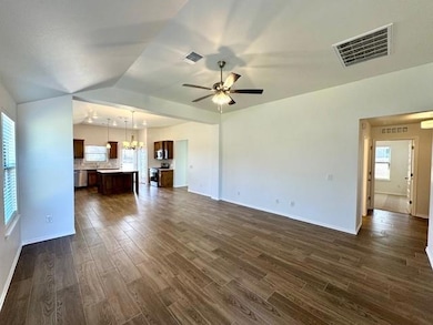 Unfurnished living room with dark wood-style flooring, a chandelier, lofted ceiling, and ceiling fan