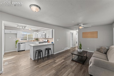 Living room featuring a textured ceiling, light wood-style flooring, and ceiling fan