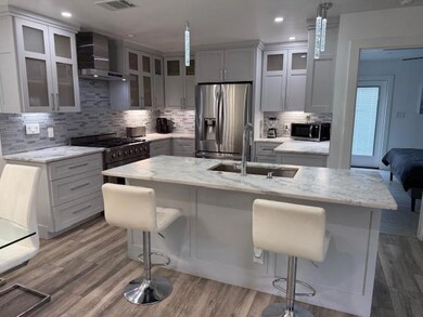 Kitchen featuring wall chimney range hood, applia