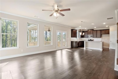 Unfurnished living room featuring crown molding, ceiling fan, dark wood-type flooring, and recessed lighting