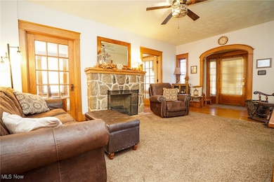 Living area with a stone fireplace and ceiling fan