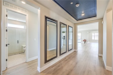 Hall with light wood-type flooring, baseboards, an