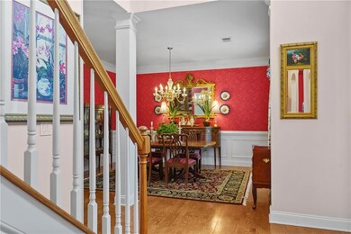 Foyer entrance with wood finished floors, ornamental molding, a wainscoted wall, a chandelier, and stairs
