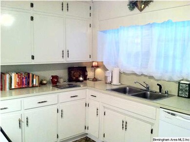 Clean white kitchen with window to sunroom.
