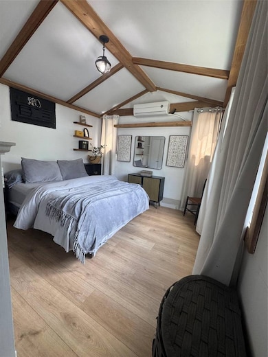 Bedroom featuring a wall mounted air conditioner and light wood-style flooring