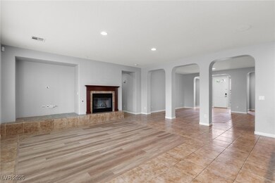 Unfurnished living room featuring recessed lighting, a tile fireplace, arched walkways, and light tile patterned floors