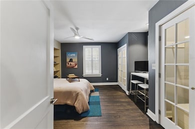 Bedroom 1 with wood finished floors, a desk, ceiling fan, and french doors