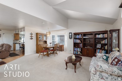 Living area featuring light carpet, a chandelier, and vaulted ceiling