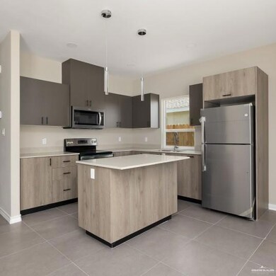 Kitchen featuring modern cabinets, stainless steel appliances, hanging light fixtures, and light tile patterned flooring