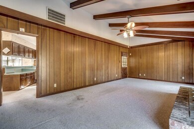 Carpeted spare room featuring ceiling fan, beamed 