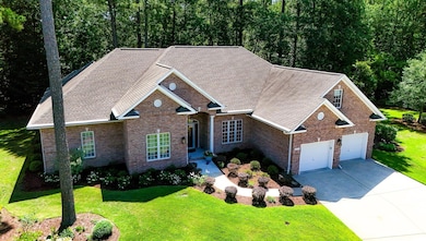Traditional-style home featuring concrete driveway, brick siding, a front lawn, and an attached garage