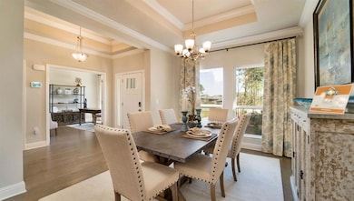 Dining room with a tray ceiling, crown molding, wood finished floors, and a chandelier