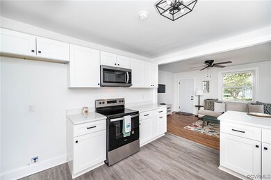 Kitchen with white cabinets, light countertops, light hardwood flooring, ceiling fan, and stainless steel appliances
