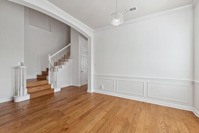 Empty room featuring an inviting chandelier, crown molding, and light wood-type flooring