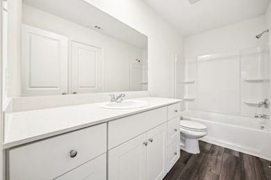 Full bath with vanity, dark wood-style flooring, and washtub / shower combination