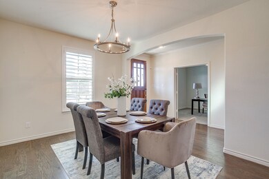 Dining room with arched walkways, dark wood-type flooring, ornamental molding, and a chandelier