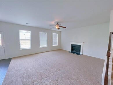 Unfurnished living room featuring a fireplace with flush hearth, carpet flooring, and ceiling fan