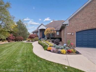 View of front of house featuring a front yard, brick siding, an attached garage, driveway, and a chimney