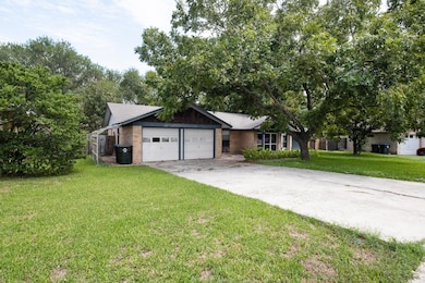 View of front facade featuring a front yard, driveway, a garage, and brick siding