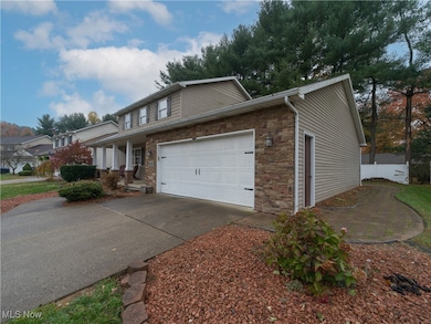 Traditional home featuring stone siding, a porch, driveway, and a garage