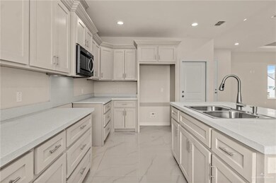 Kitchen with white cabinetry, sink, and light stone counters