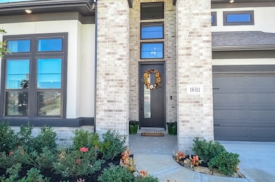 This home features a modern brick exterior with a welcoming front door. Large windows provide ample natural light, and a well-maintained garden adds charm to the entrance.