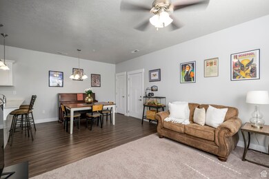 Living room with dark wood-style floors, a ceiling fan, a textured ceiling, and a chandelier