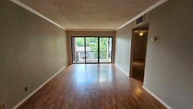 Empty room featuring wood finished floors, a textured ceiling, ornamental molding, and a ceiling fan