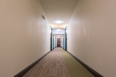 Corridor featuring carpet flooring and baseboards