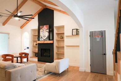 Living room featuring arched walkways, ceiling fan, light wood finished floors, beamed ceiling, and high vaulted ceiling